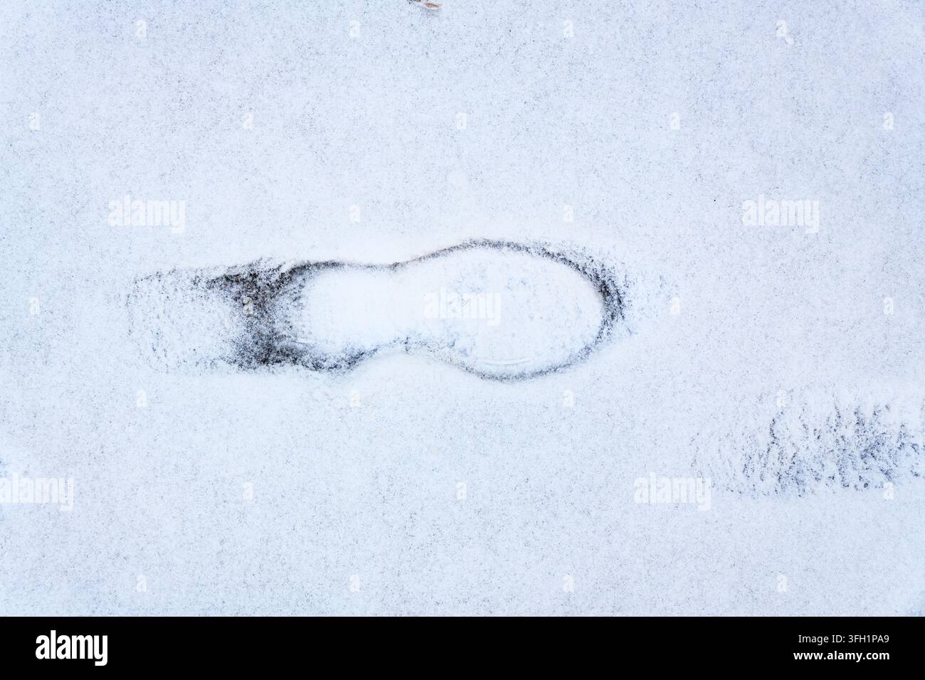 Unica impronta di piede premuta nella neve fresca invernale Foto Stock