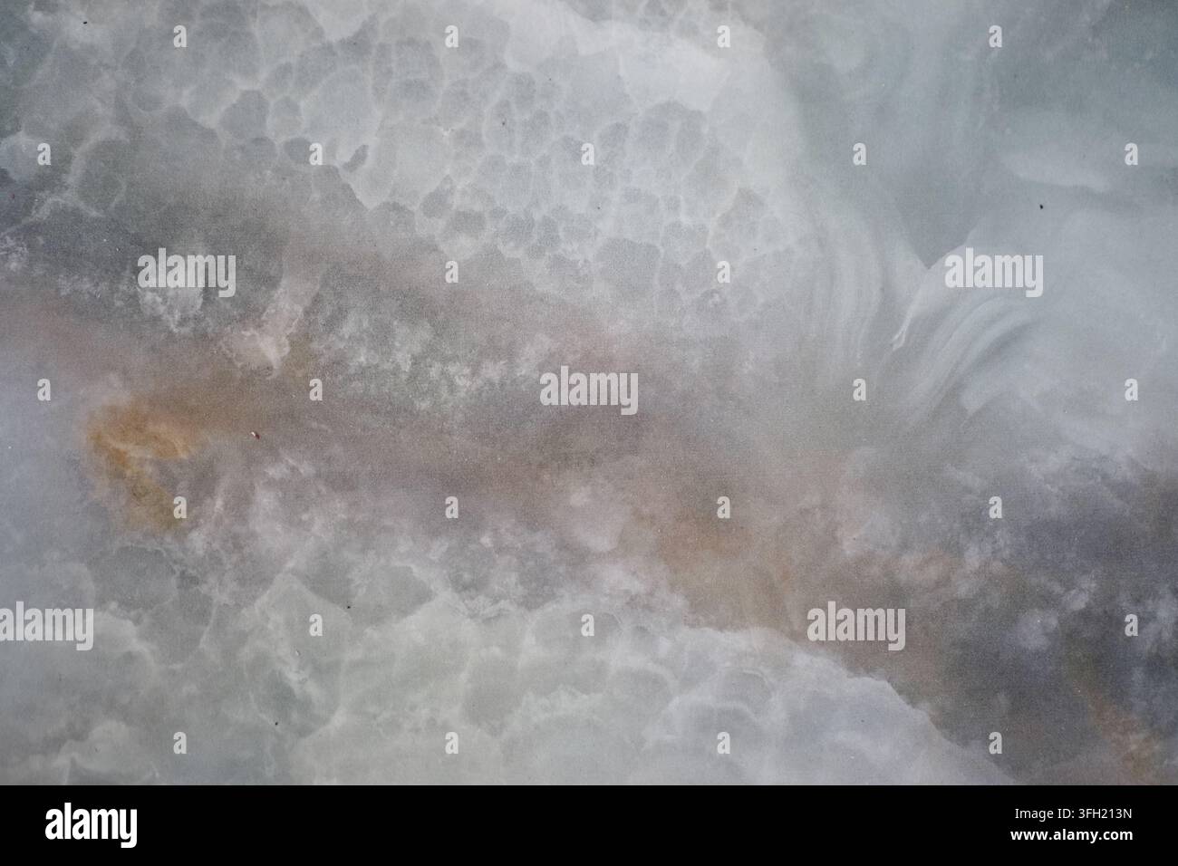Vista ravvicinata di una lastra di pietra naturale in marmo o onice con motivi nuvolosi e venati Foto Stock