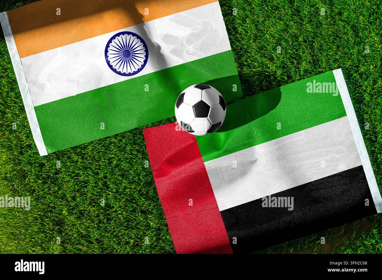 Partita di calcio India vs. Emirati Arabi Uniti. Bandiere nazionali su erba verde con un pallone da calcio al centro. Sfondo di calcio per una partita internazionale Foto Stock