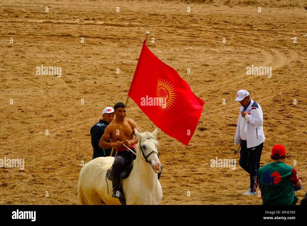 Partecipante della lotta equestre o Er Enish, con bandiera kirghisa durante i World Nomad Games 2026 in Kirghizistan. Foto Stock