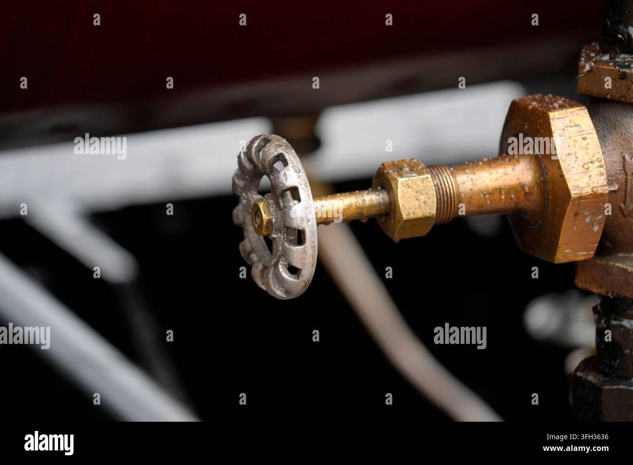 Prima di una valvola a saracinesca in ottone invecchiata con una manovella in ghisa, che mostra ruggine e gocce d'acqua sull'equipaggiamento industriale. Foto Stock