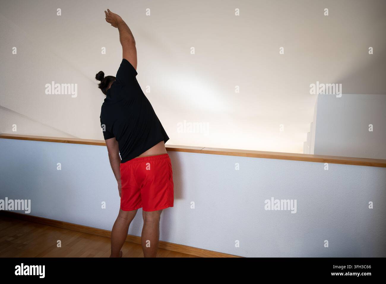 Uomo che allunga i muscoli laterali durante l'allenamento al chiuso Foto Stock