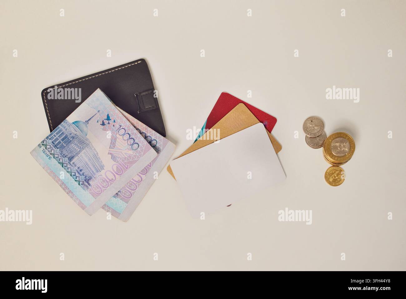 Banconote in tengé kazako, un portafoglio aperto e monete disposte su una superficie luminosa, rappresentanti finanze personali, spese, risparmi Foto Stock