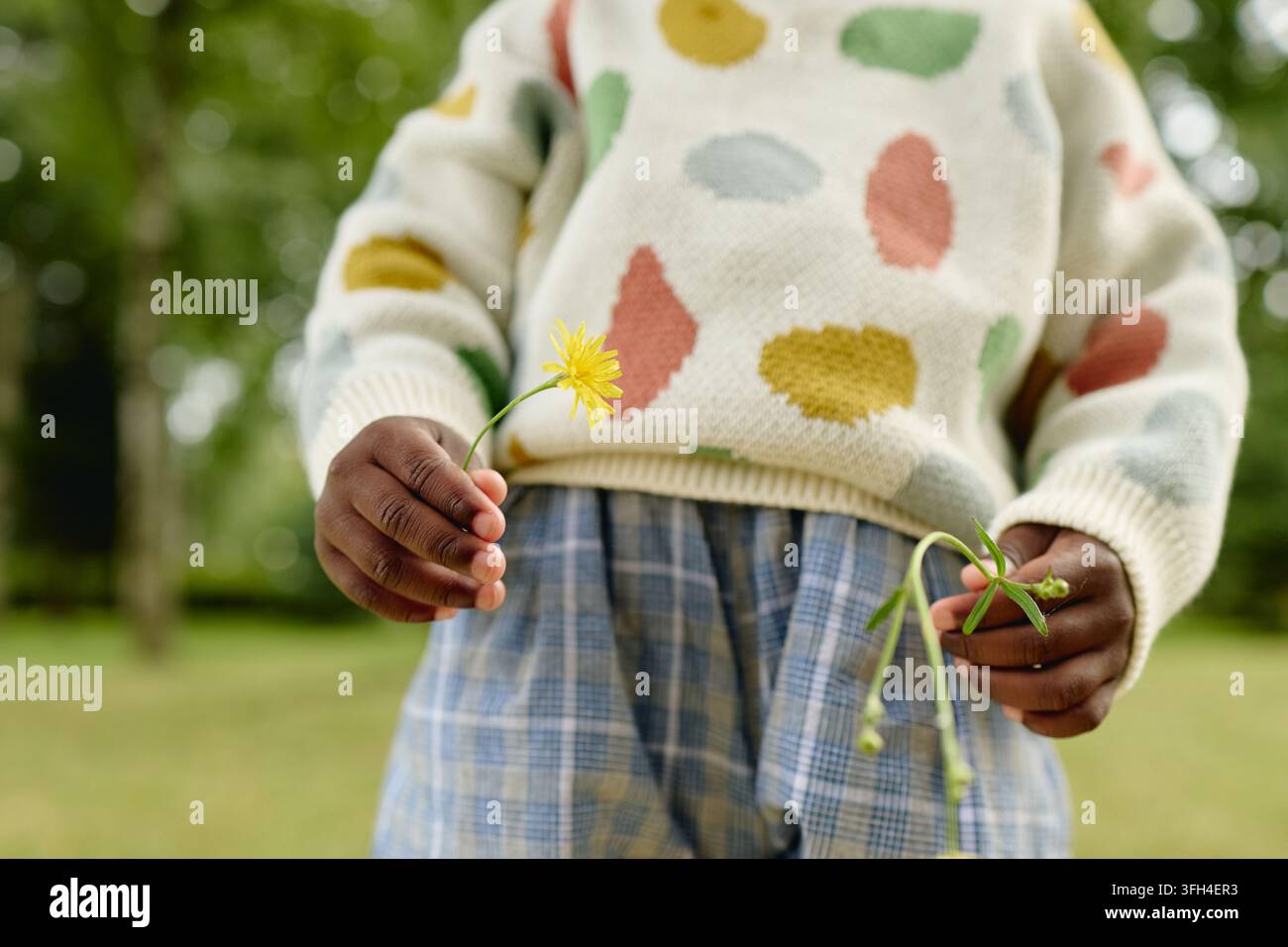 Ragazza afroamericana che tiene fiori selvatici in un parco all'aperto Foto Stock