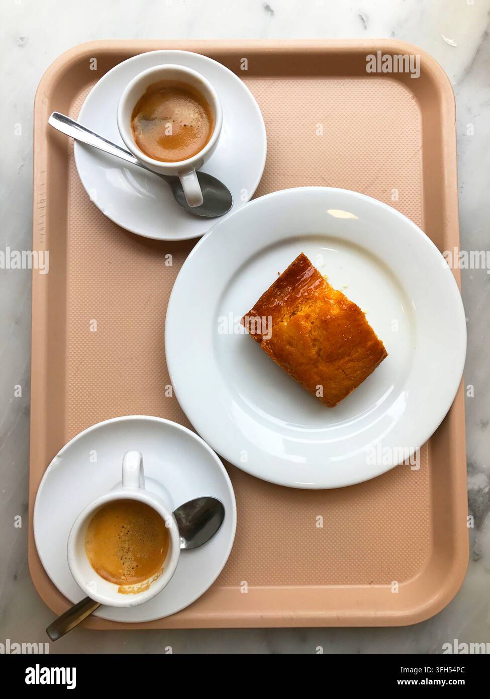 Due tazze di caffè e un pezzo di pan di Spagna su un vassoio. Vista dall'alto. Foto Stock