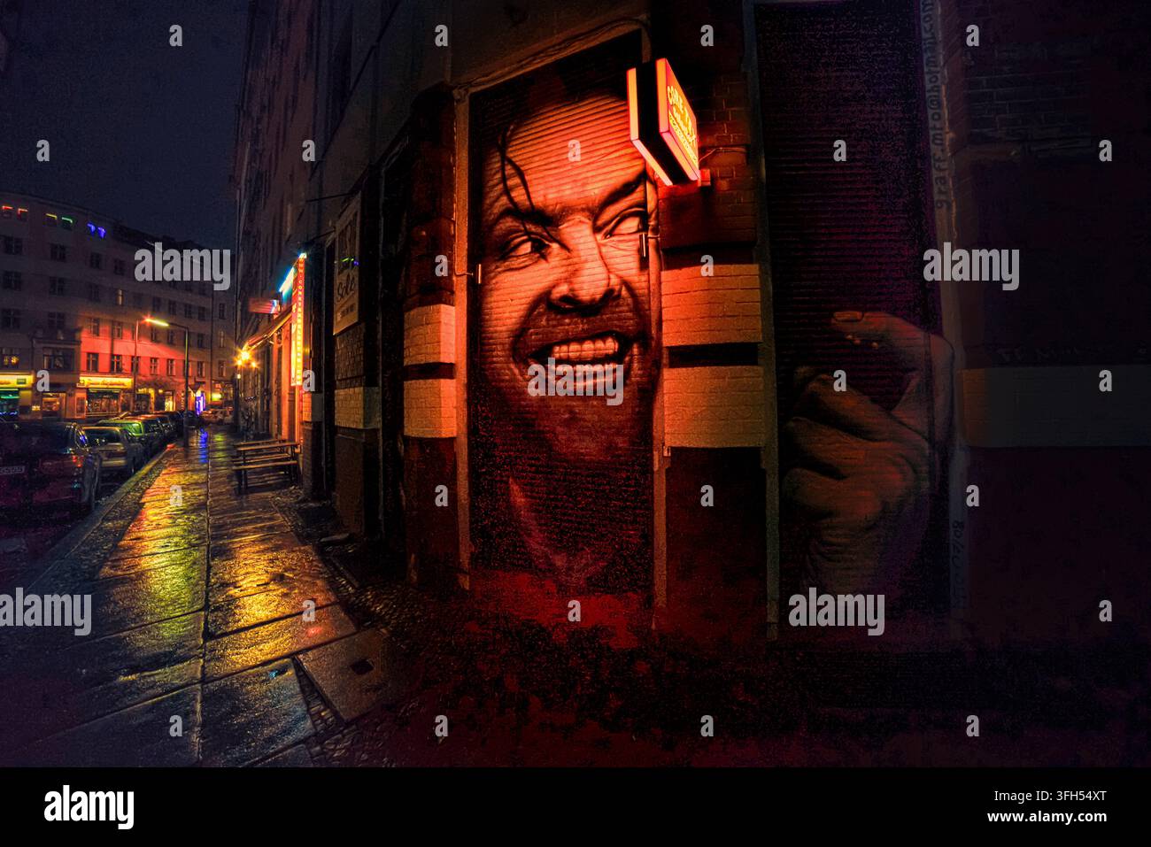 Affresco di un volto ghignante (Jack Nicholson) che risplende di rosso di notte, porta di arte di strada, Mariannenplatz, Kreuzberg, Berlino Foto Stock