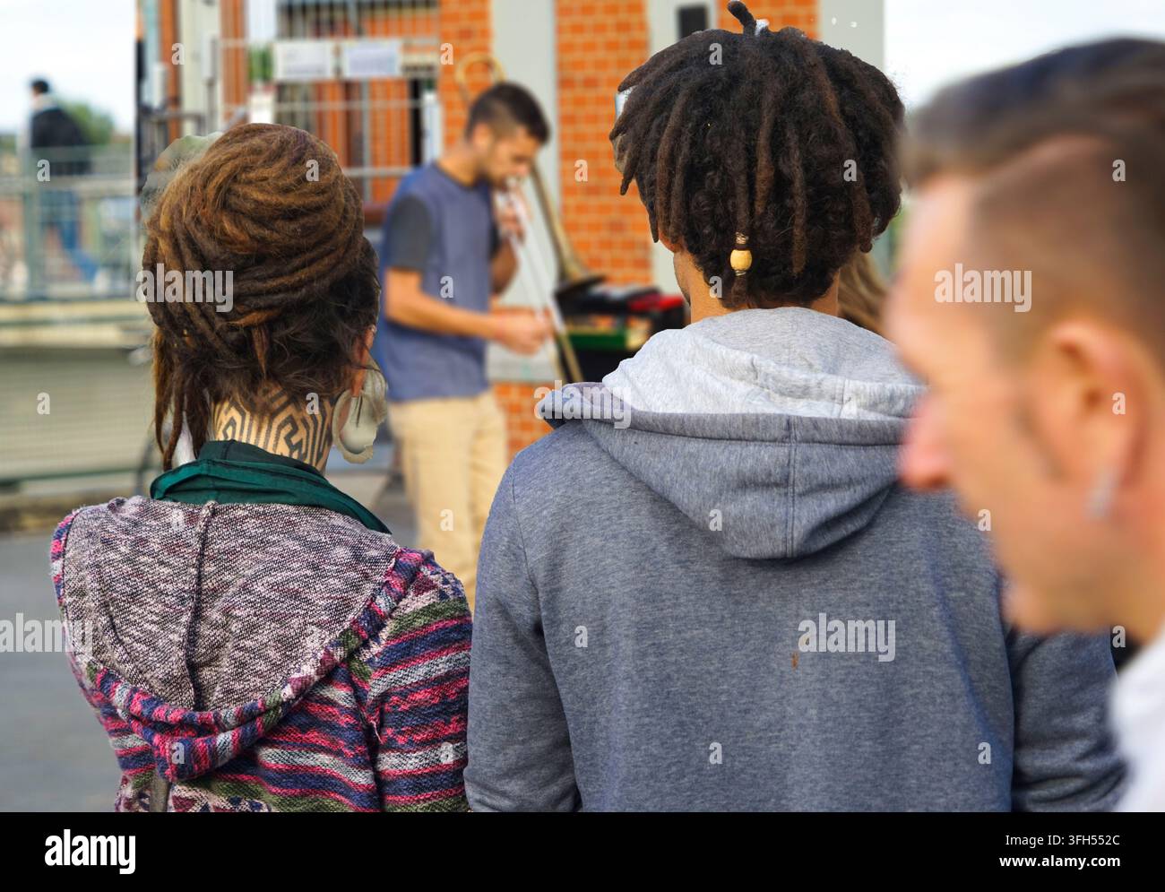 Amici con dreadlocks osservano una performance di strada, atmosfera di sottocultura urbana, Friedrichshain, Berlino Foto Stock