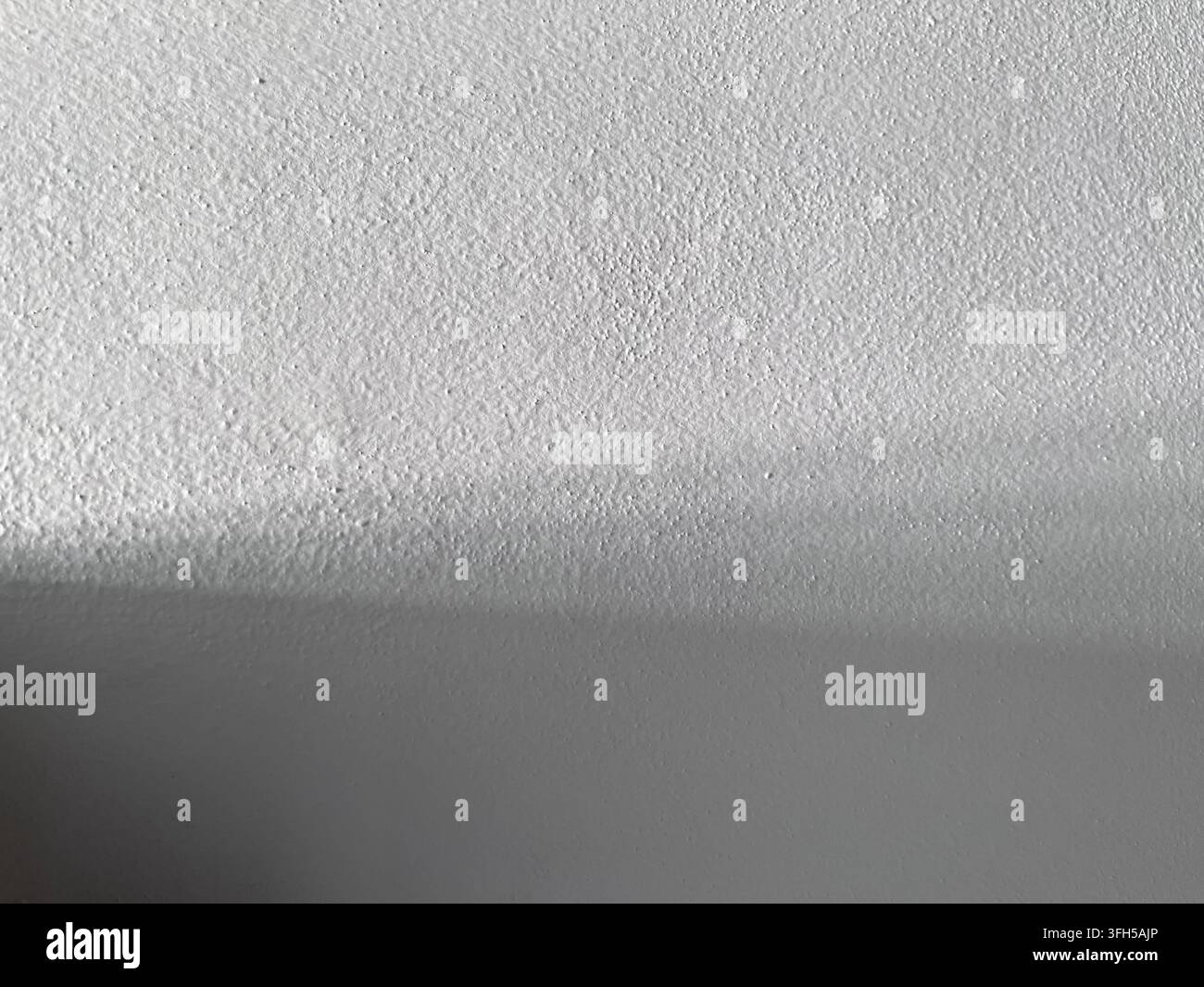Muro astratto grigio strutturato con ombra morbida e superficie di cemento sottile Foto Stock