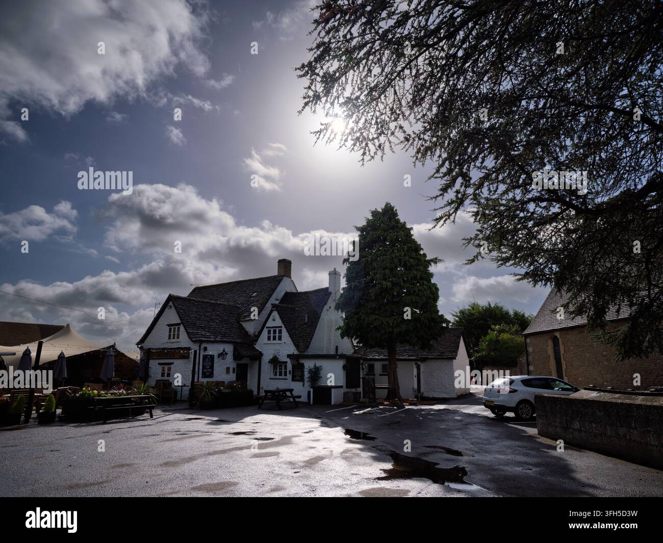 Pub tradizionale in pietra dei Cotswold, The Old George Inn a South Cerney, Gloucestershire, Inghilterra, Regno Unito, con architettura storica in una giornata di sole Foto Stock