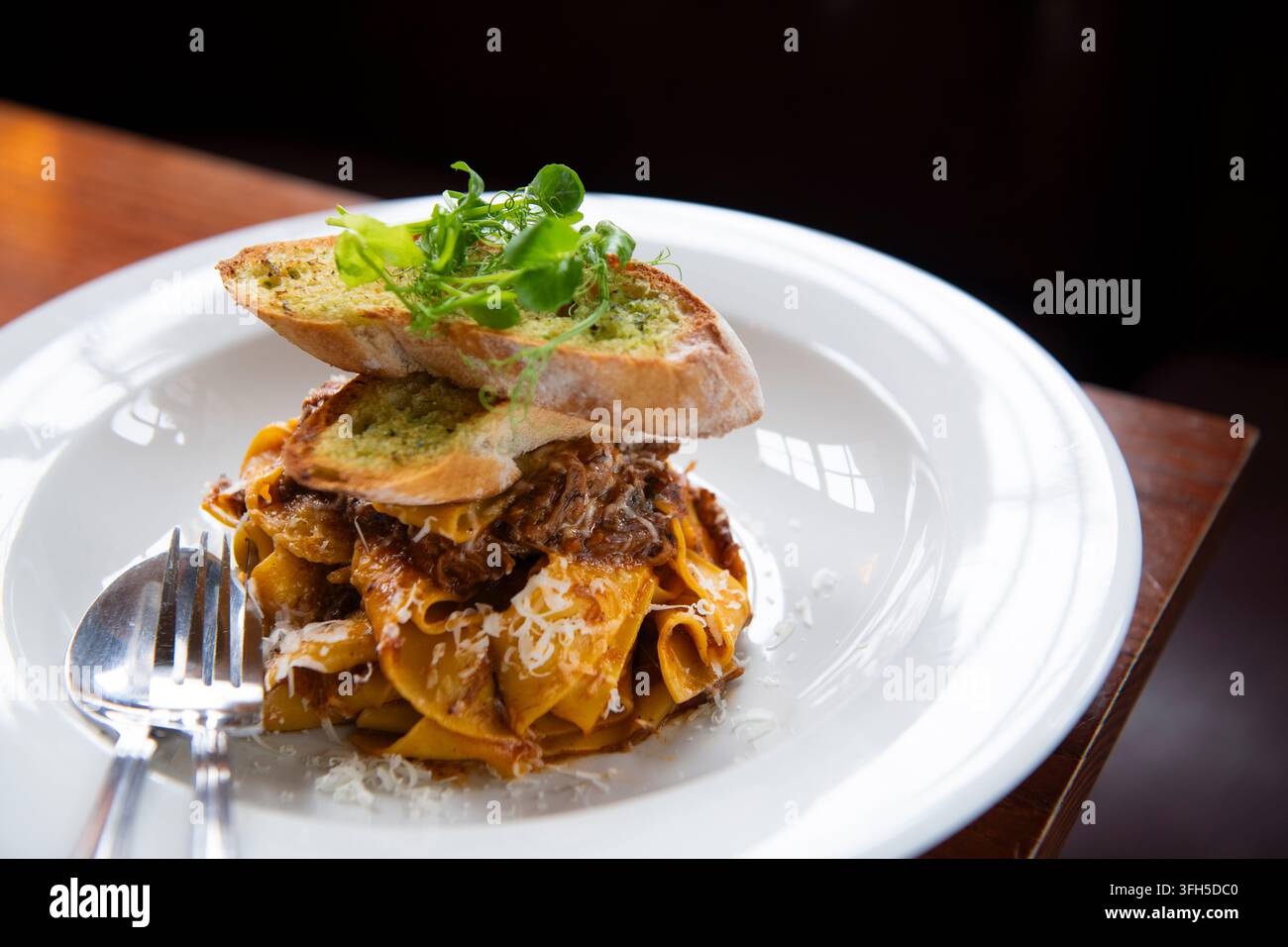 Pasta tagliatelle condita con carne saporita, verdure fresche e pane croccante invita all'indulgenza. Foto Stock