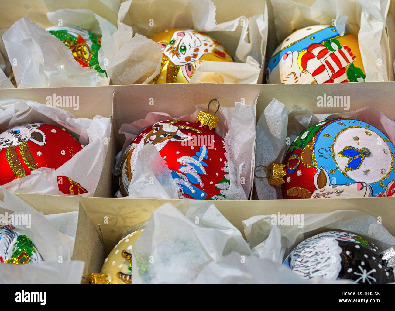 Prima vista di ornamenti colorati e fatti a mano per l'albero di Natale disposti ordinatamente in una scatola con divisori e carta velina. Foto Stock