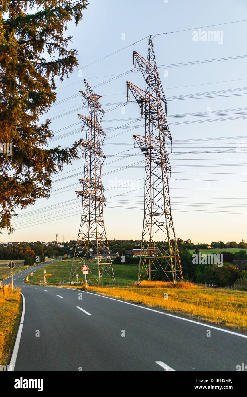 Strada rurale tortuosa sotto piloni ad alta tensione in Germania Foto Stock