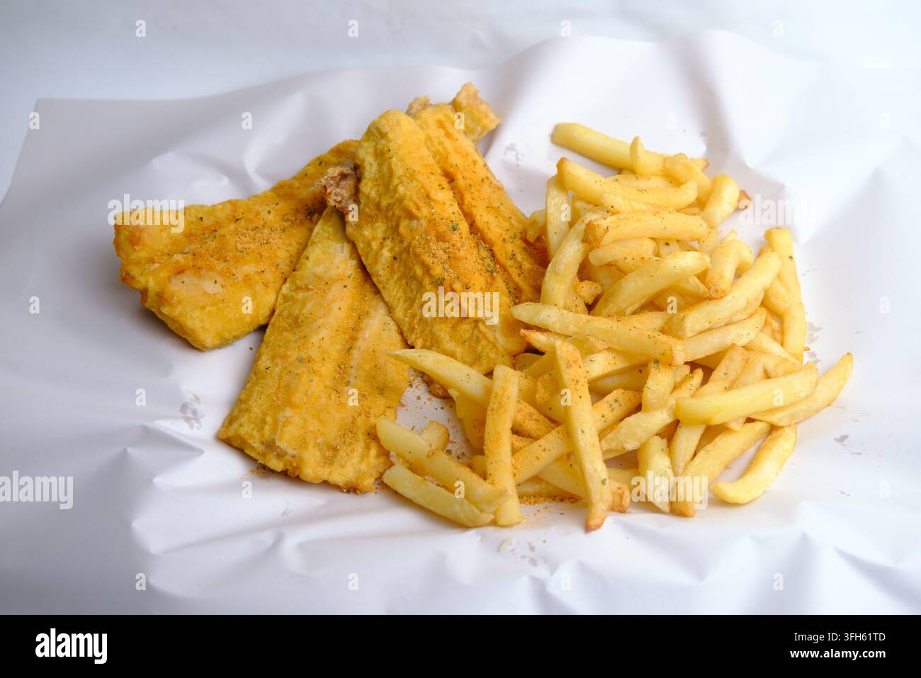 Una grande porzione di pesce impanato fritto e patatine su carta di sfondo bianca come pasto da asporto Foto Stock
