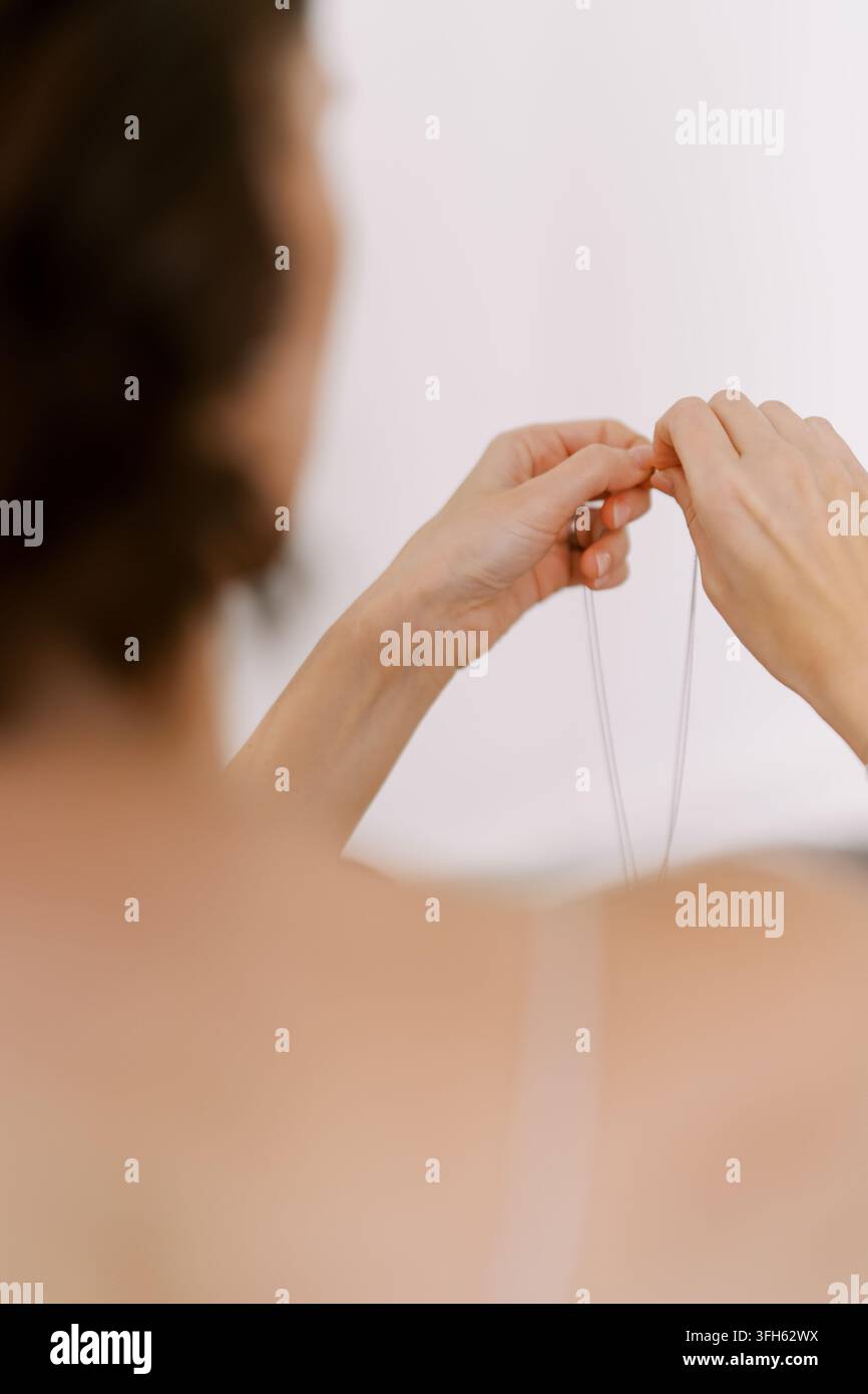 Donna che tiene una collana delicata con entrambe le mani Foto Stock