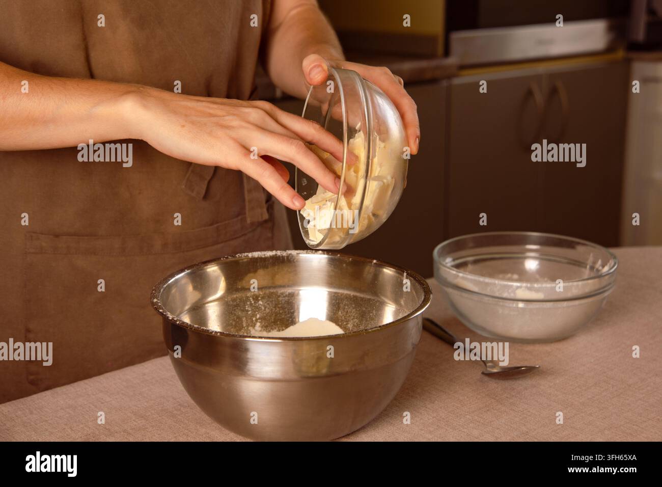 Donna che aggiunge burro freddo a cubetti a una ciotola di farina, preparando l'impasto per la pasta fatta in casa Foto Stock