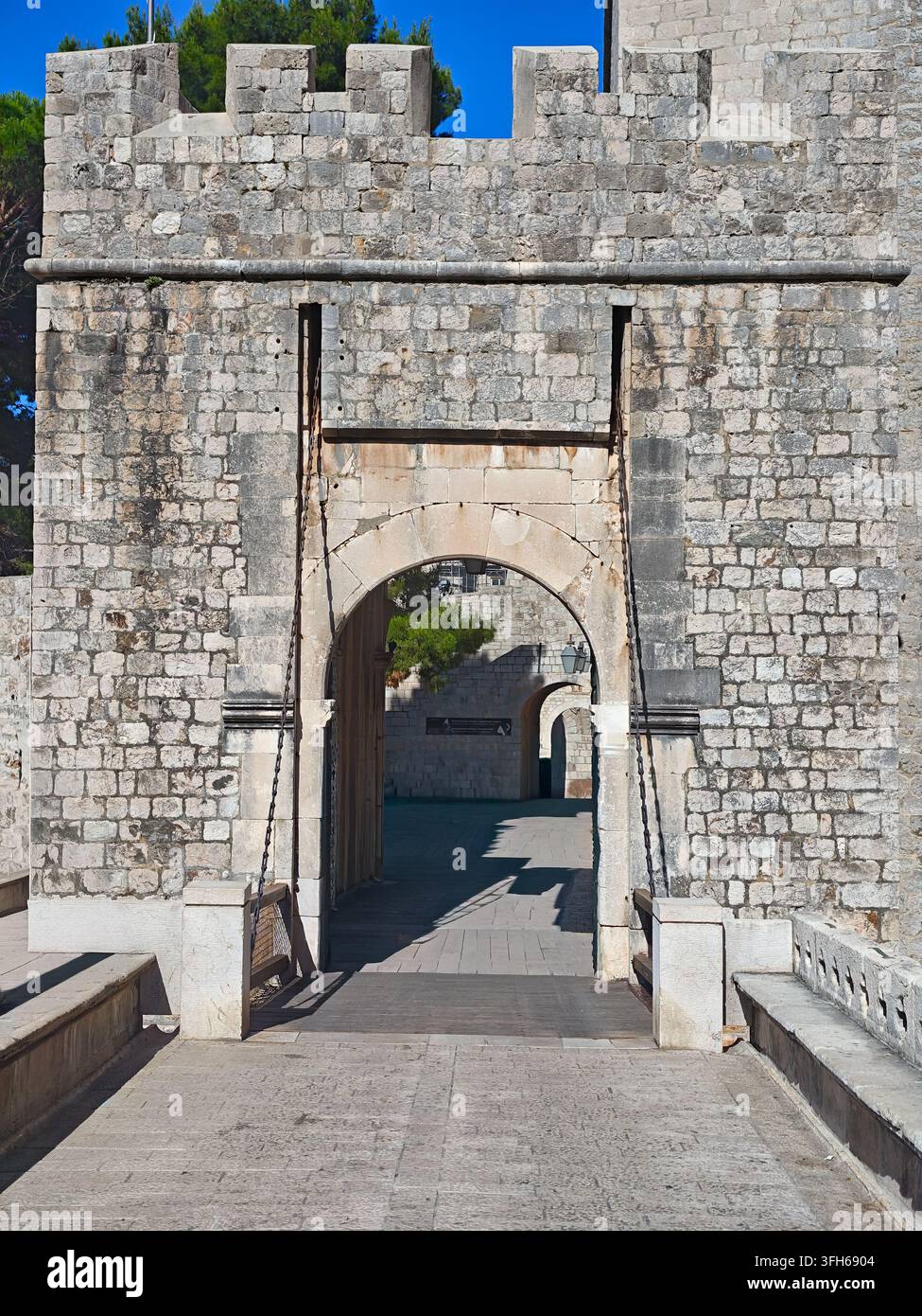 Una giornata soleggiata che mette in risalto le mura di pietra erose, l'ingresso ad arco e le catene del ponte levatoio della storica fortezza della Porta di Ploce. - Immagine stock catturata con smartphone