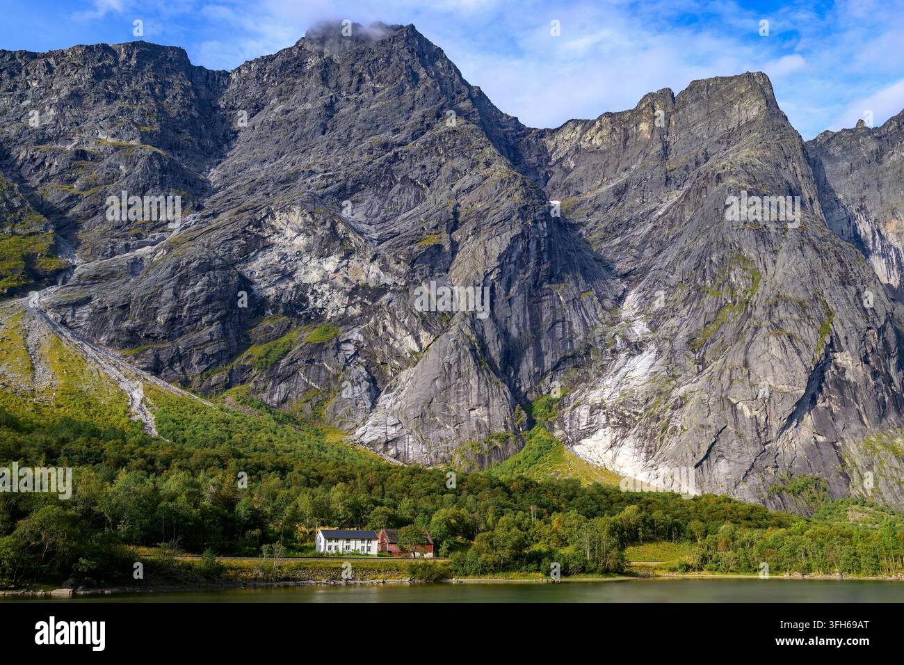 La fattoria Lökken di fronte alle ripide montagne Breidtind (1797 m) e Trollryggen (a destra, 1725 m) a Romsdal, nella Norvegia occidentale. Foto Stock
