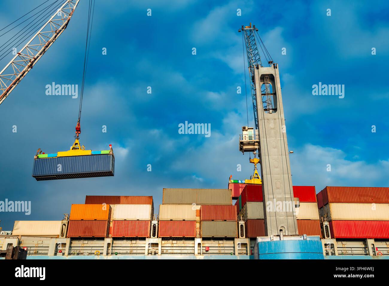 Grane industriali caricano container navali su una nave da carico durante le operazioni di trasporto marittime in un porto commerciale. Foto Stock