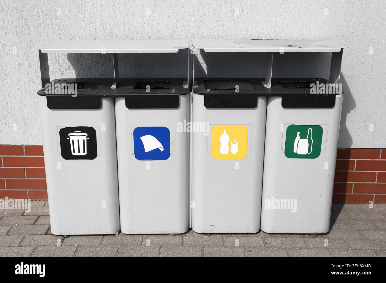 Bidoni per lo smaltimento dei rifiuti con simboli di riciclo colorati disposti all'aperto. Sfondo di riciclo per la separazione dei rifiuti, la sostenibilità e la gestione dei rifiuti. Foto Stock
