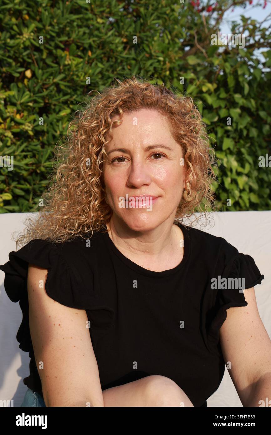 Ritratto di una bella donna bionda di mezza età con capelli ricci Foto Stock