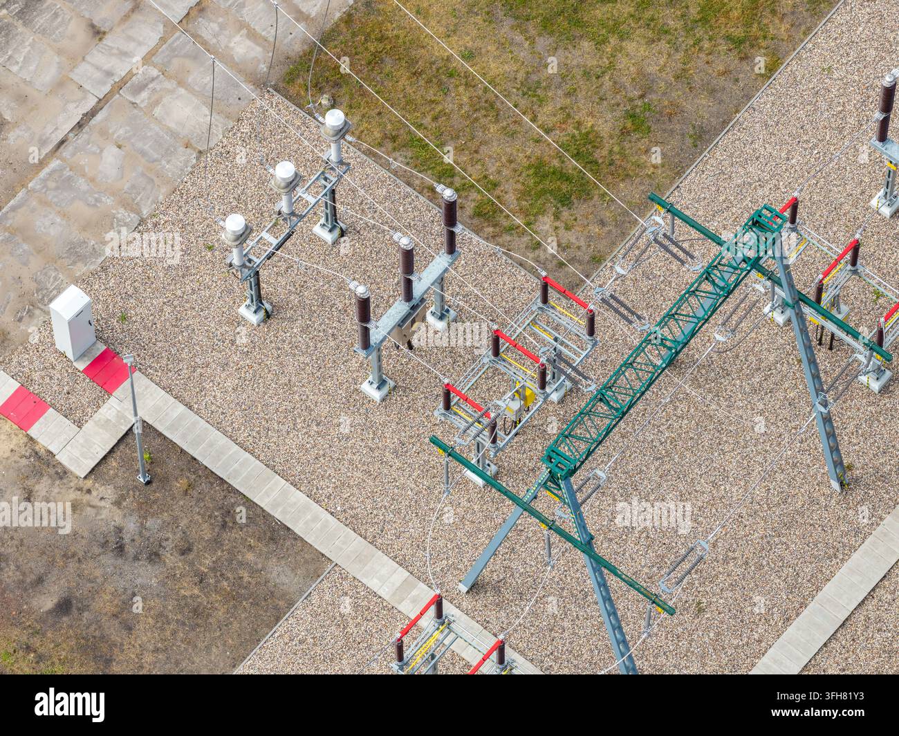 Vista aerea di una sottostazione elettrica con apparecchiature ad alta tensione, strutture metalliche e terreno in ghiaia in Polonia. Foto Stock