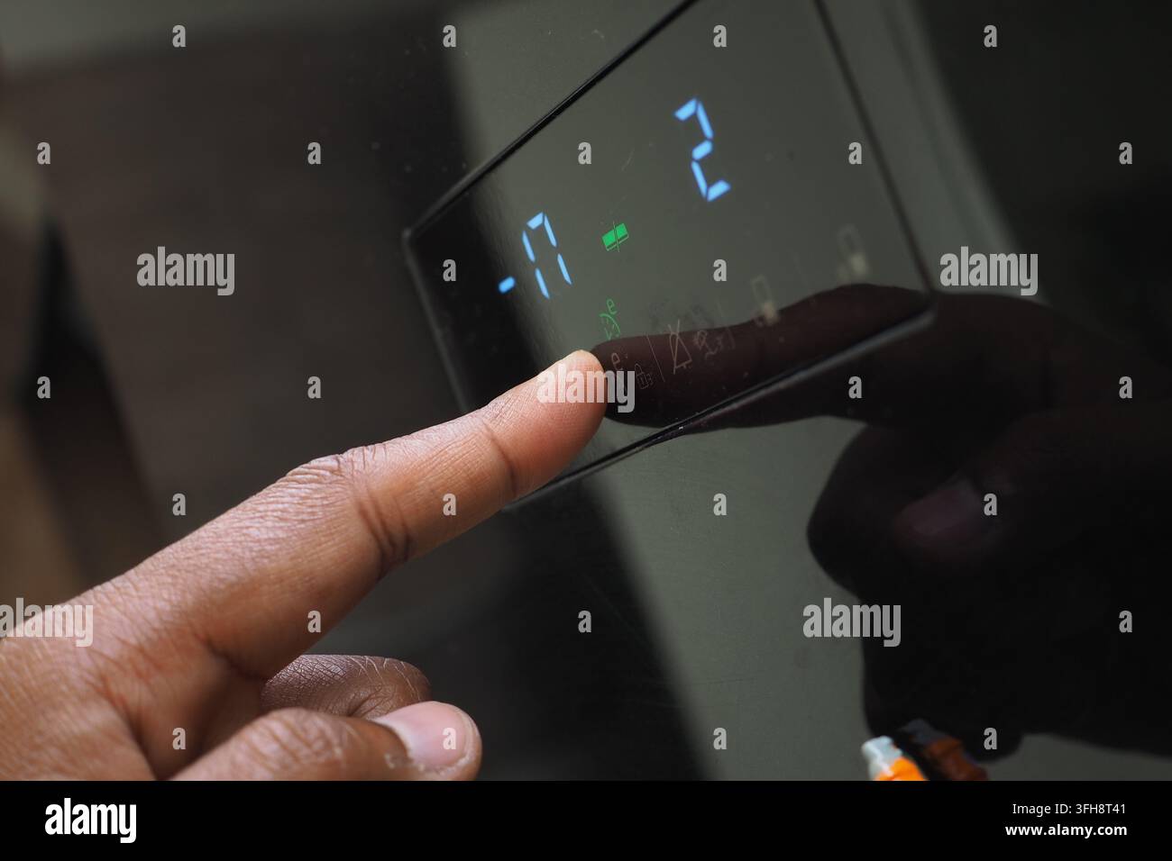 Un uomo indica il display digitale per regolare l'impostazione della temperatura su un frigorifero. Foto Stock