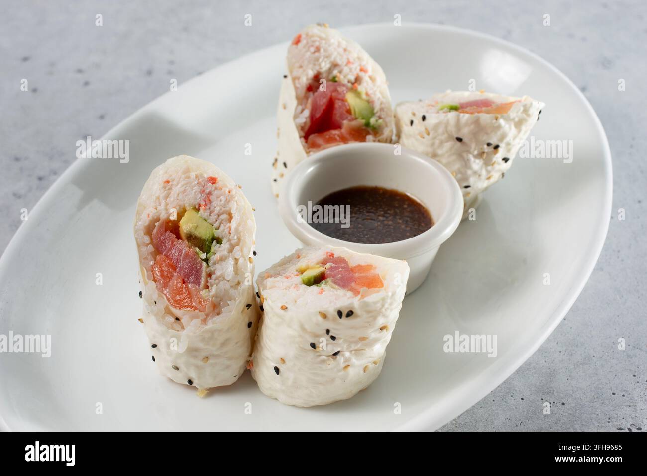 Una vista di un rotolo di sushi, con salmone, tonno e avocado. Foto Stock