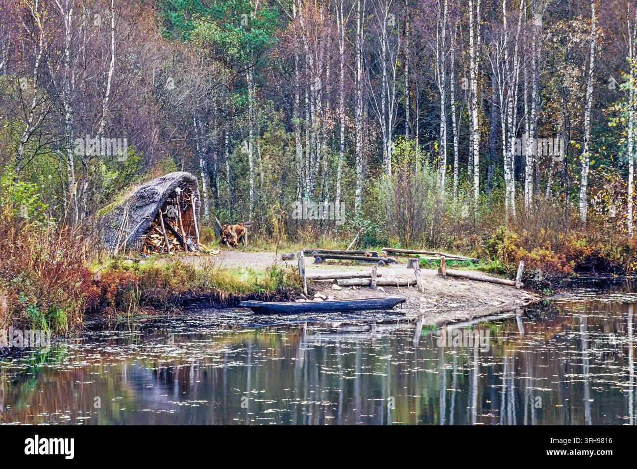 Capanne su una spiaggia con una barca di legno nell'acqua Foto Stock