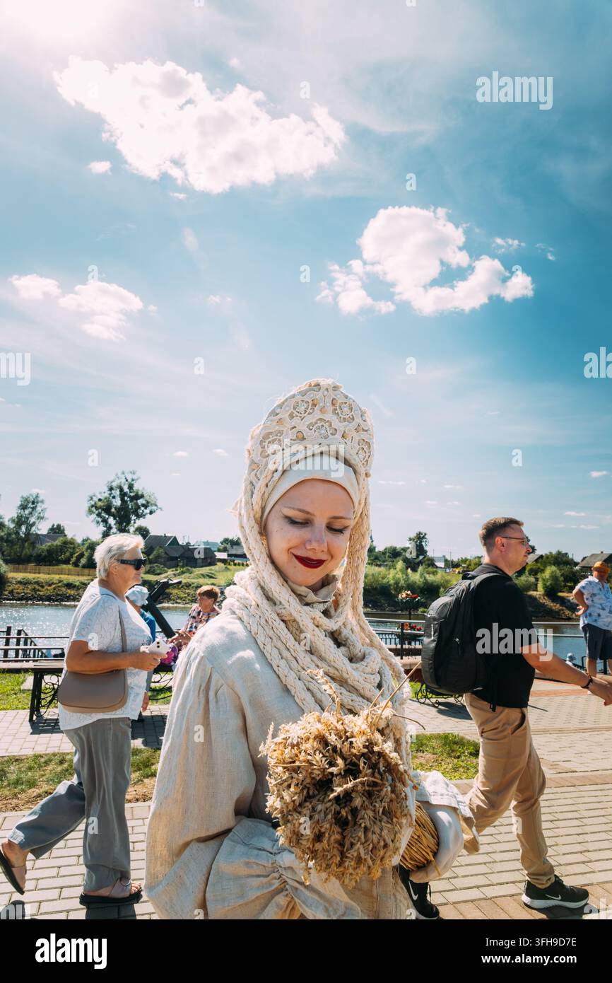Ritratto di una performer femminile con un copricapo bianco ornato e un costume accanto al fiume Pripjat. Foto Stock