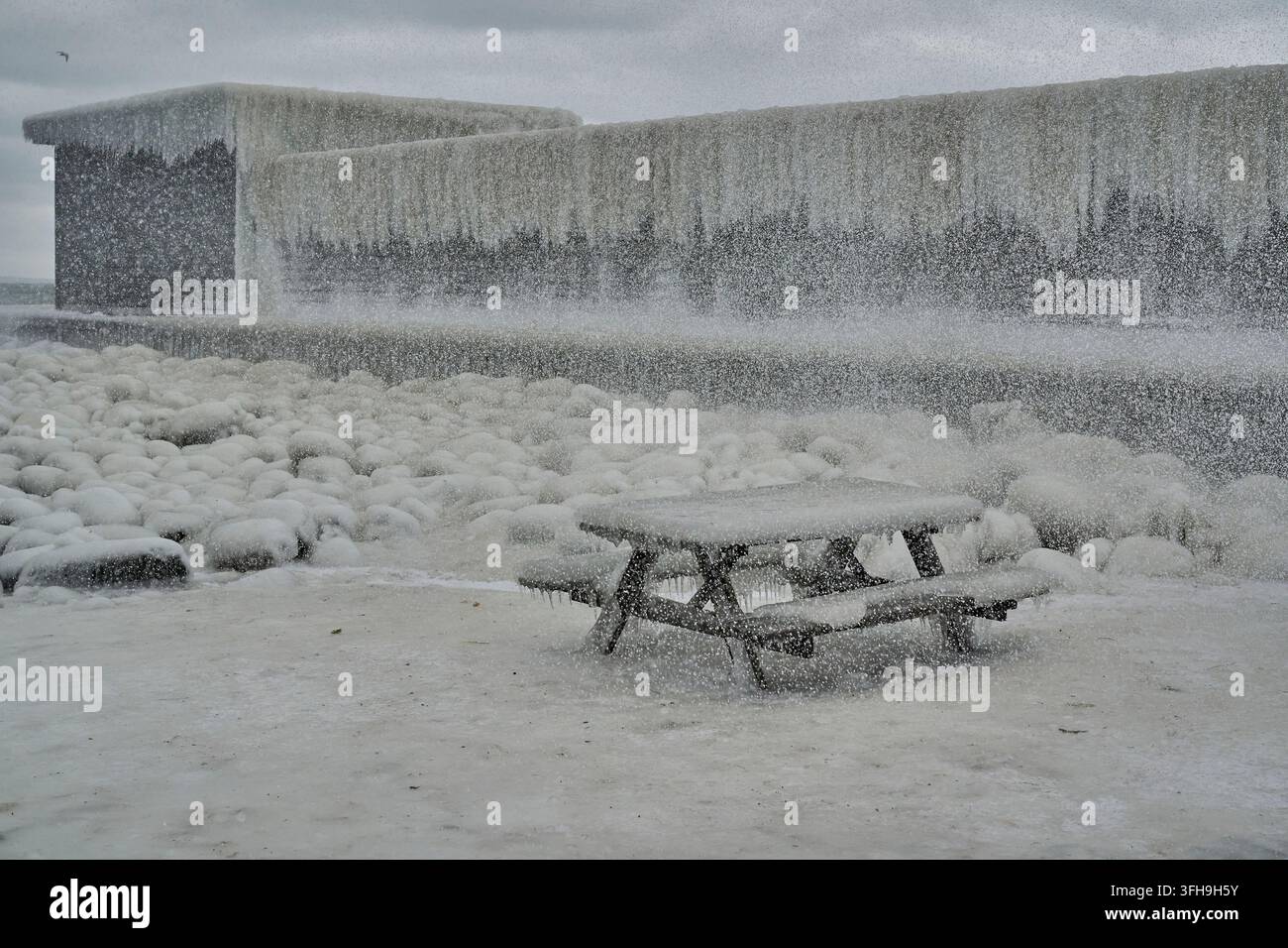 Inverno ghiacciato in Danimarca - Tavolo da giardino ghiacciato - Lo stabilimento balneare ghiacciato sullo sfondo Foto Stock