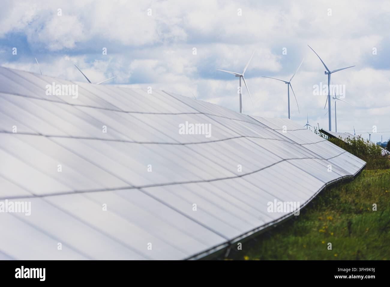 Panelli solari e turbine eoliche che generano energia rinnovabile in un paesaggio rurale sotto nuvole drammatiche. Foto di alta qualità Foto Stock