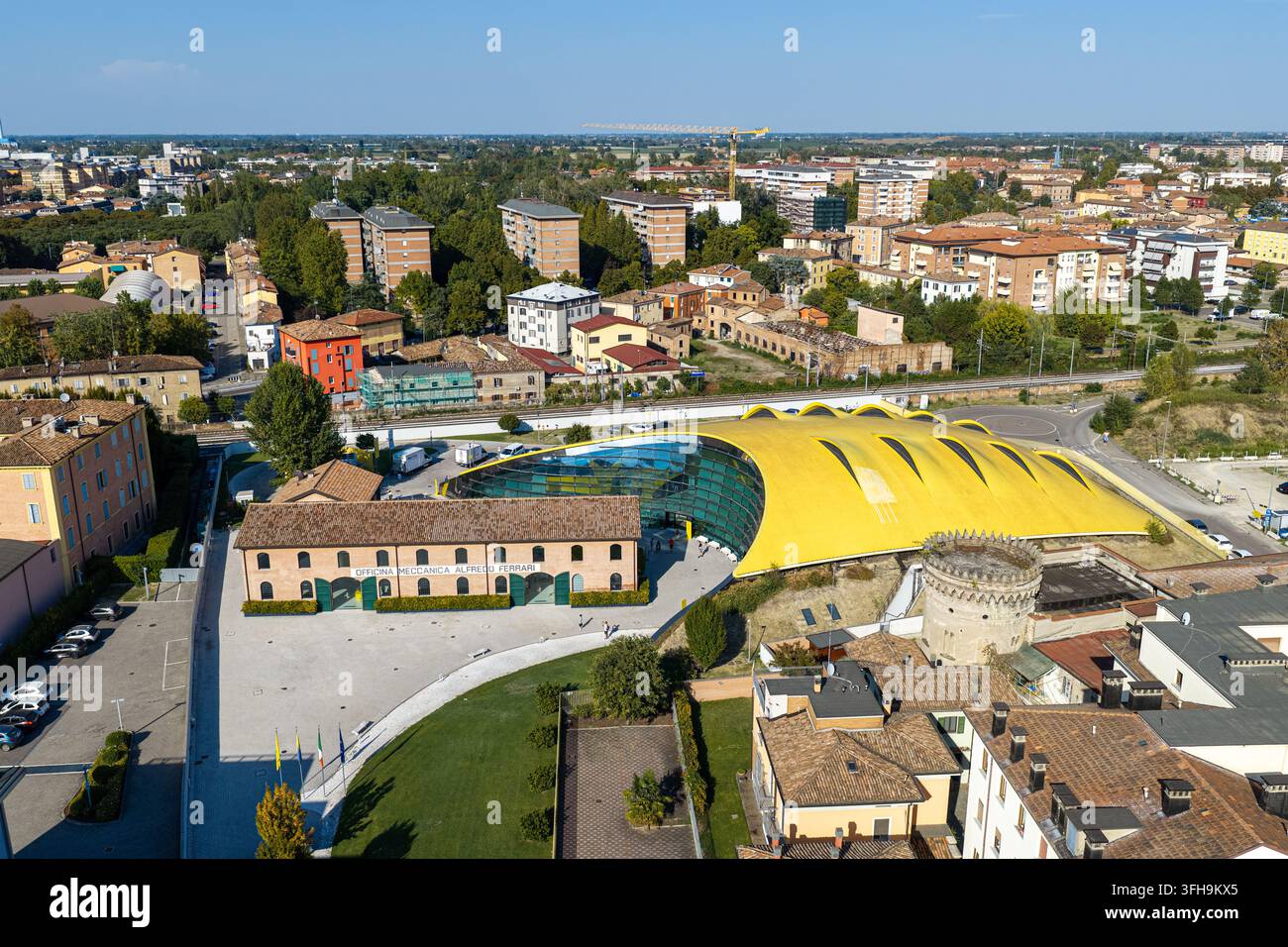 Vista aerea del Museo Enzo Ferrari con il suo tetto giallo distintivo e la facciata in vetro accanto all'edificio storico in mattoni a Modena, Emilia-Romagna Foto Stock