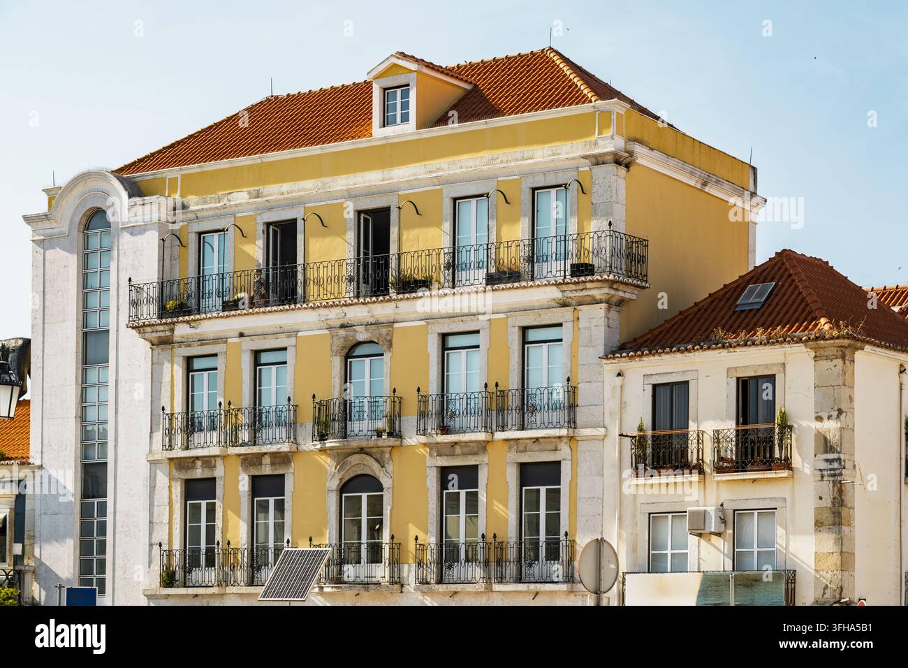 Vista di un edificio storico giallo con balconi in ferro ornati e tegole di terracotta a Setubal, Setubal, Portogallo. Foto Stock