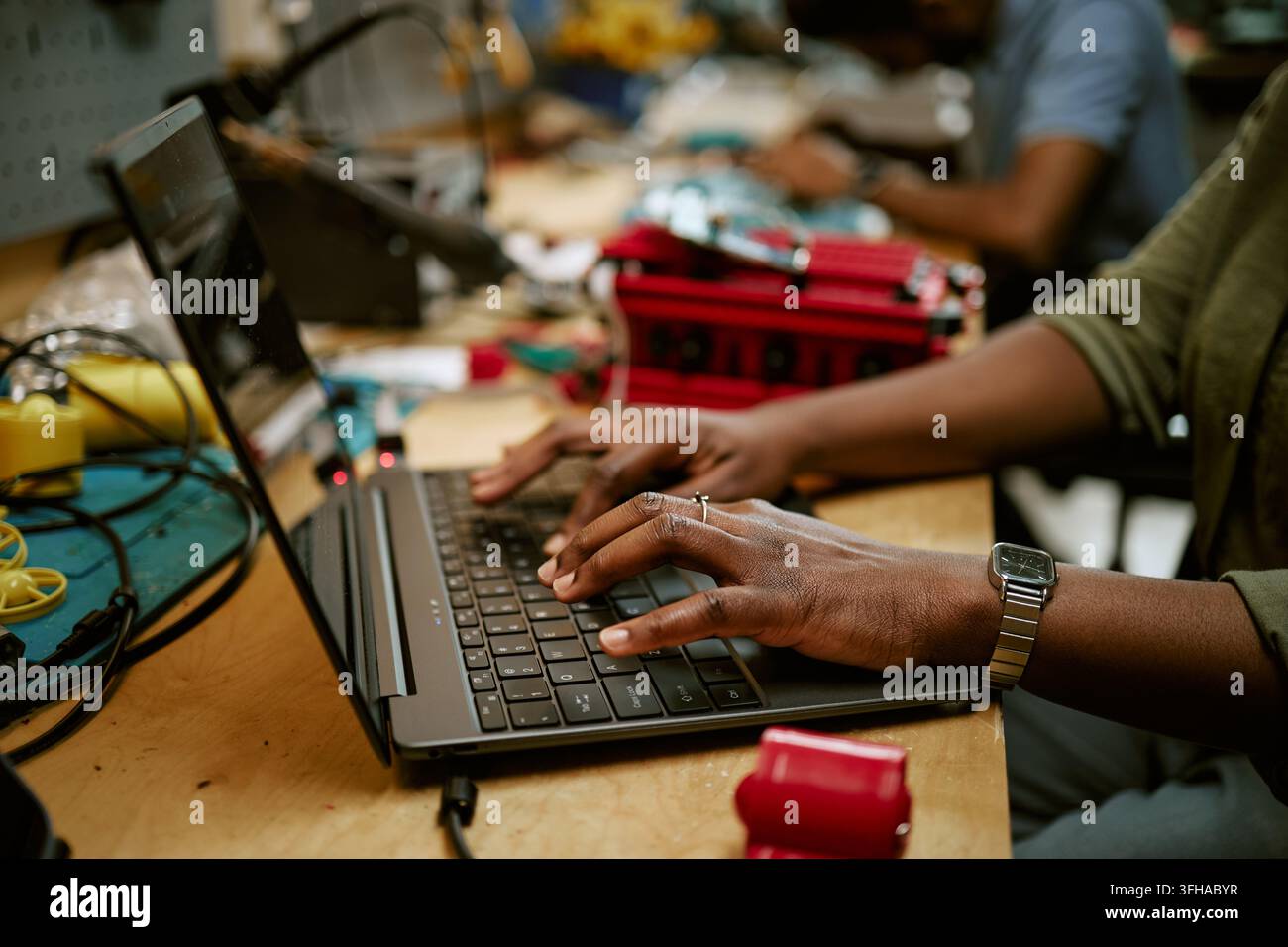 Donna nera che digita su un laptop in un laboratorio di elettronica Foto Stock