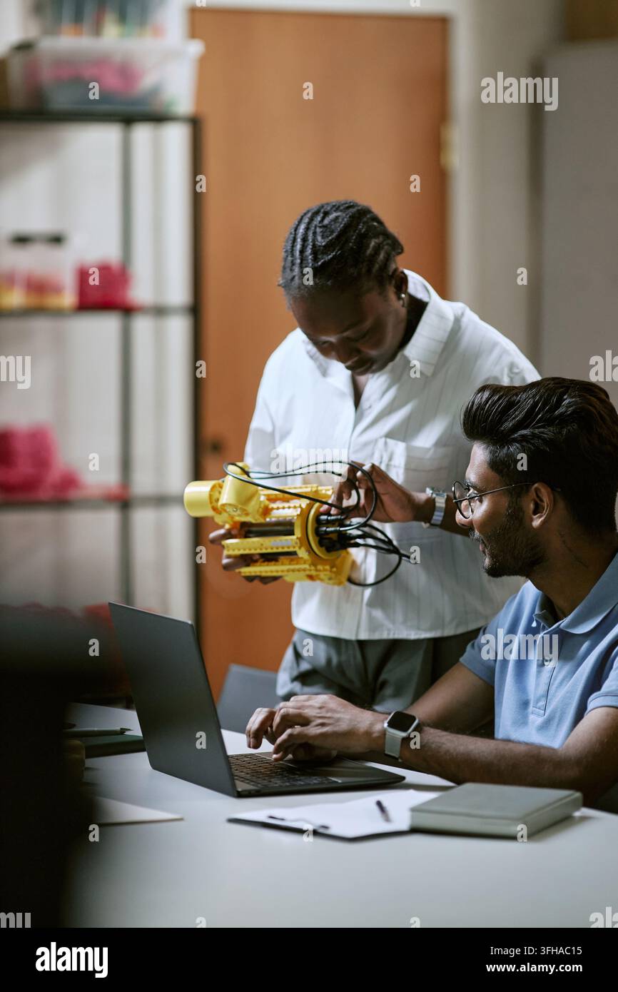 Ingegneri diversi che testano un prototipo robotico con un laptop Foto Stock
