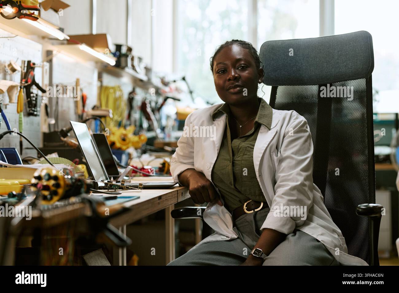 Ritratto di un'ingegnere nera sicura di sé seduta in officina Foto Stock