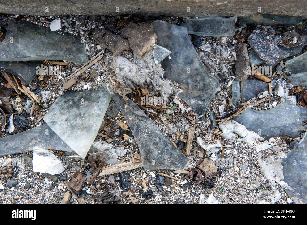 Fragmenti di vetro rotti, sporcizia e detriti da costruzione sul terreno Foto Stock