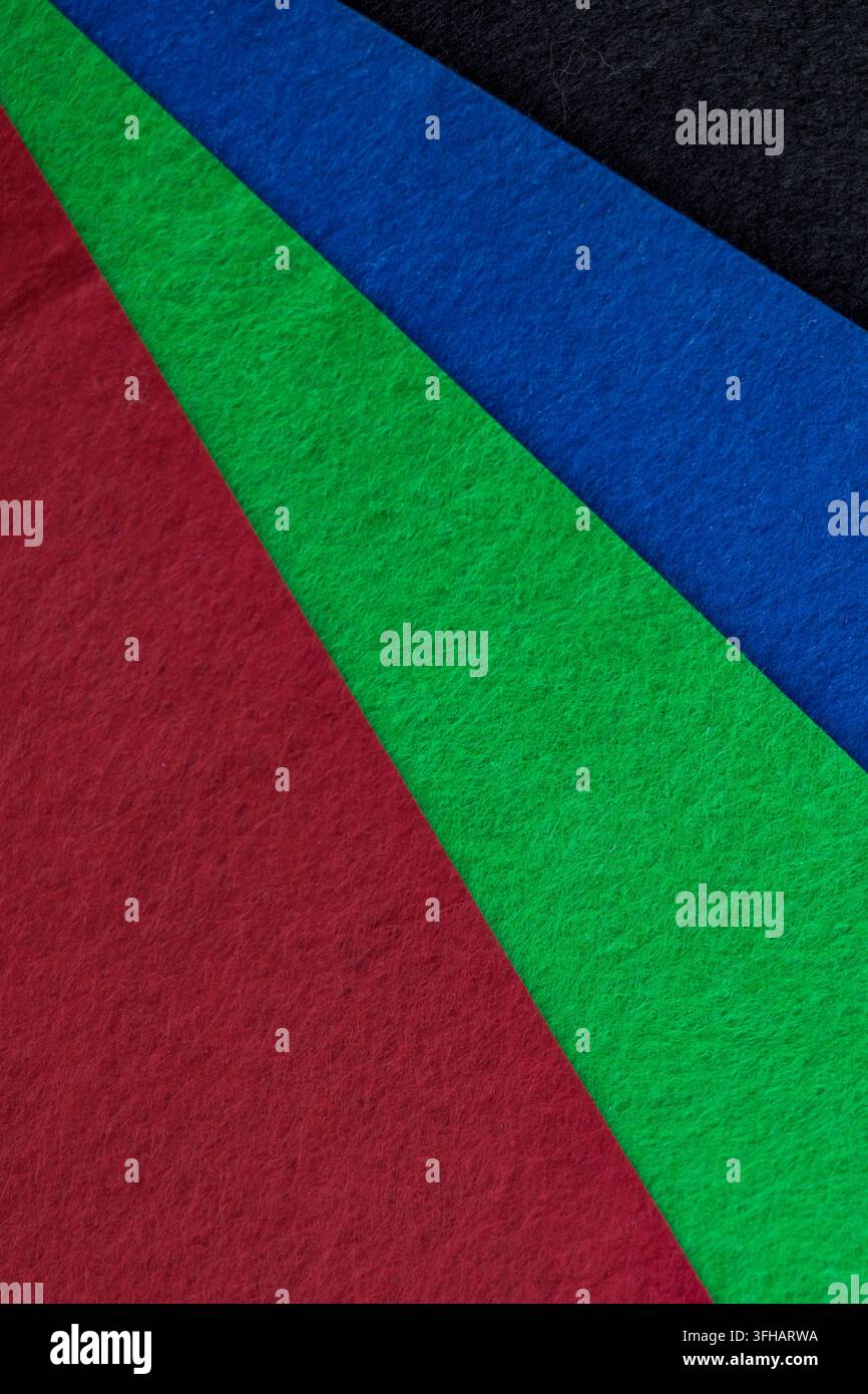 Superfici tessurate rosse, verdi e blu formano forme diagonali sovrapposte. La composizione astratta rappresenta colore, geometria e contrasto visivo Foto Stock