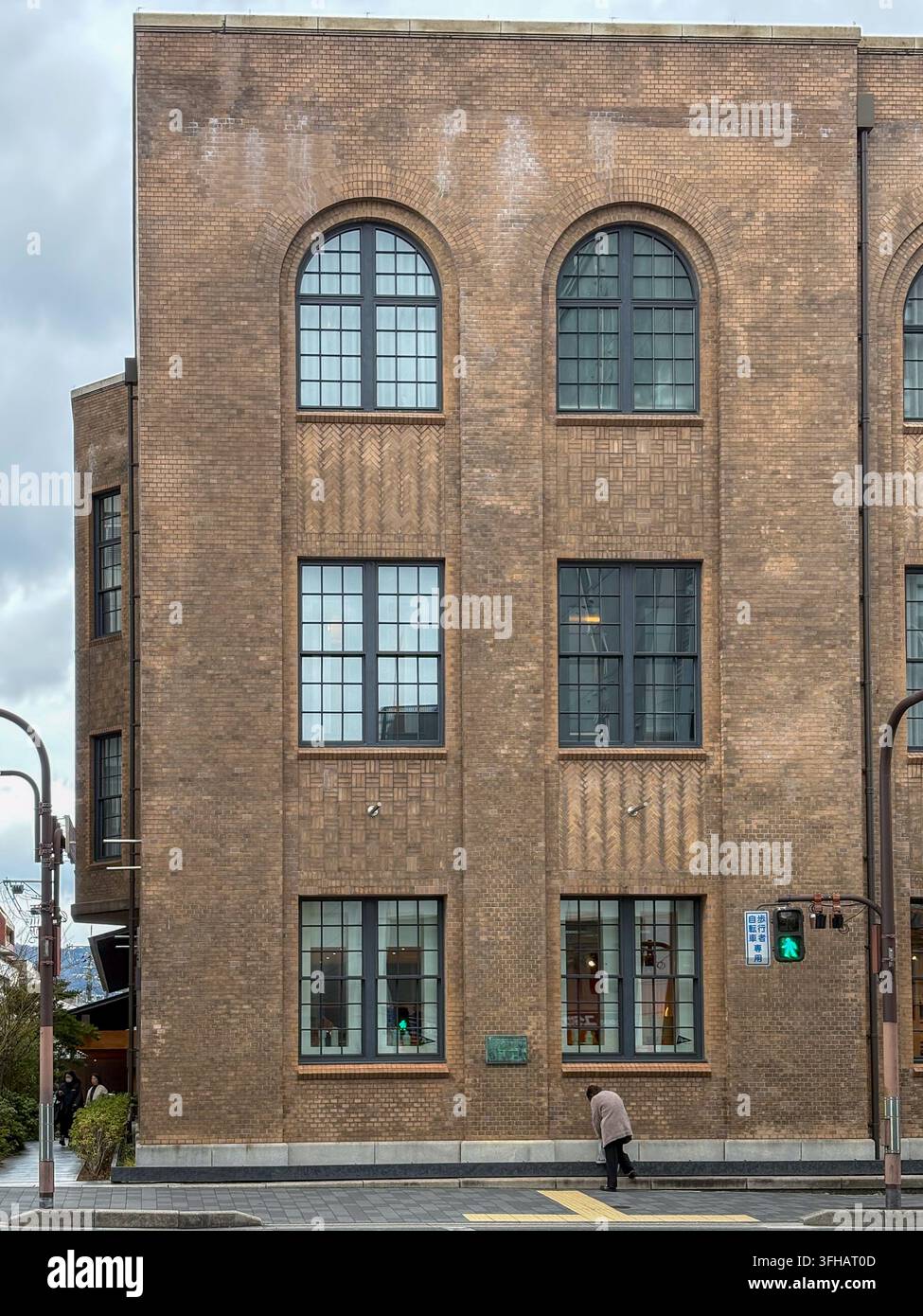 Facciata architettonica di un edificio storico in mattoni marroni con finestre ad arco a Kyoto, Giappone. - Immagine stock catturata con smartphone