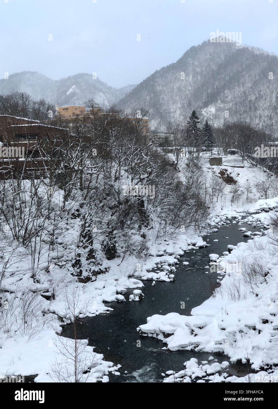 Paesaggio innevato di fiume e montagne a Jozankei Onsen, Hokkaido, Giappone in inverno - Immagine stock catturata con smartphone