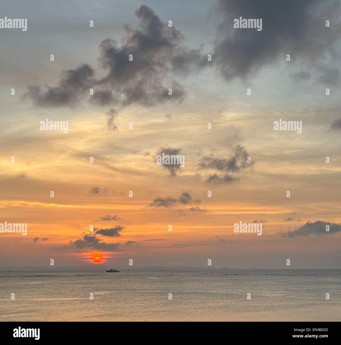 Tramonto arancione sul mare sotto nuvole drammatiche a Okinawa, Giappone - Immagine stock catturata con smartphone