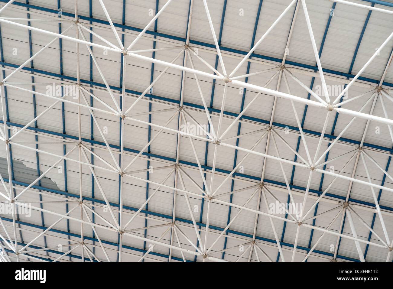 Vista ad angolo basso di un moderno soffitto geometrico in acciaio bianco a tralicci e di una struttura di supporto del tetto. Foto Stock