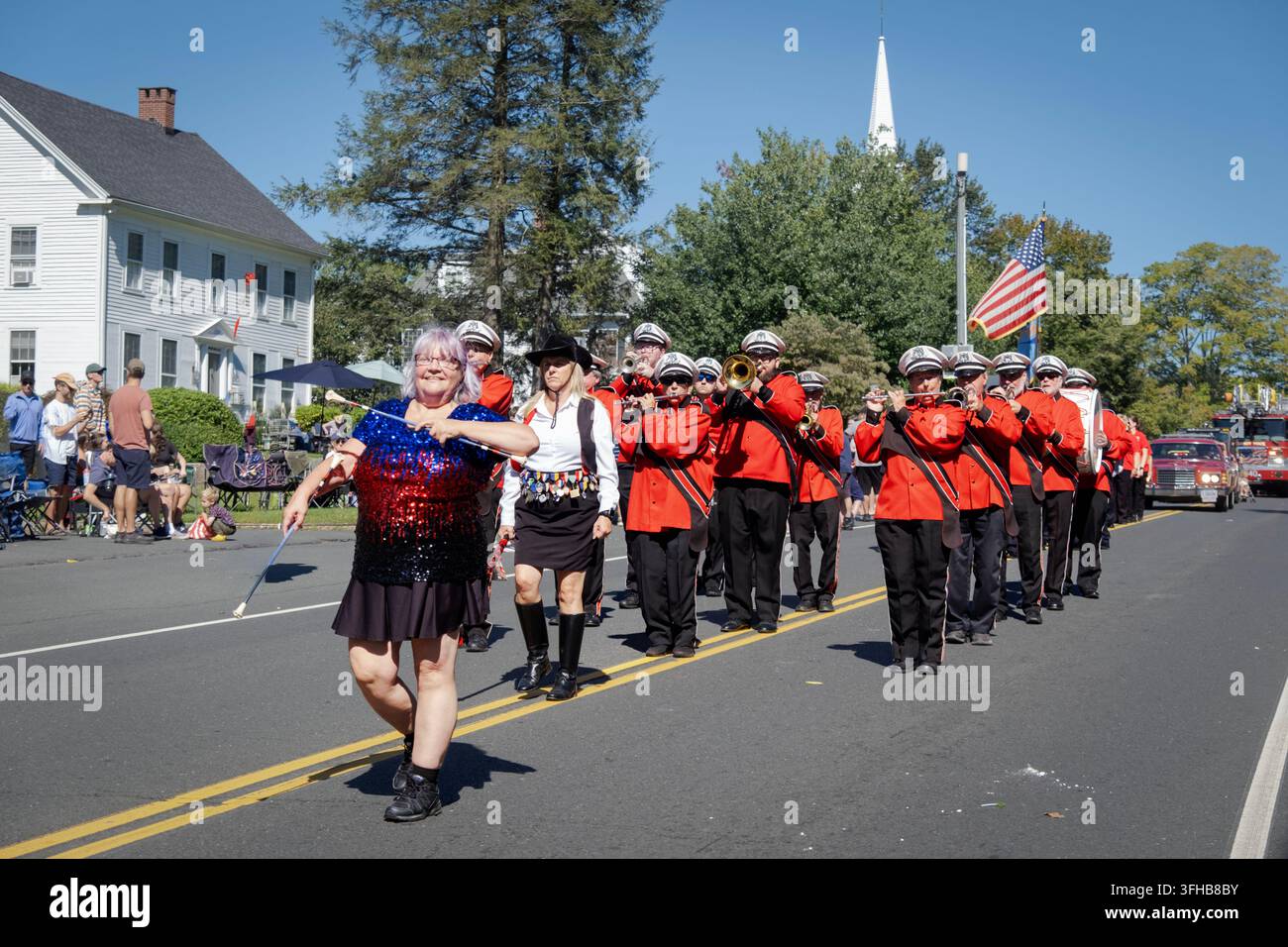 Una donna anziana che twirla la mazza guida una banda marciando lungo la via principale durante la parata del Labour Day di Newtown nel 2026 nel Connecticut. Foto Stock