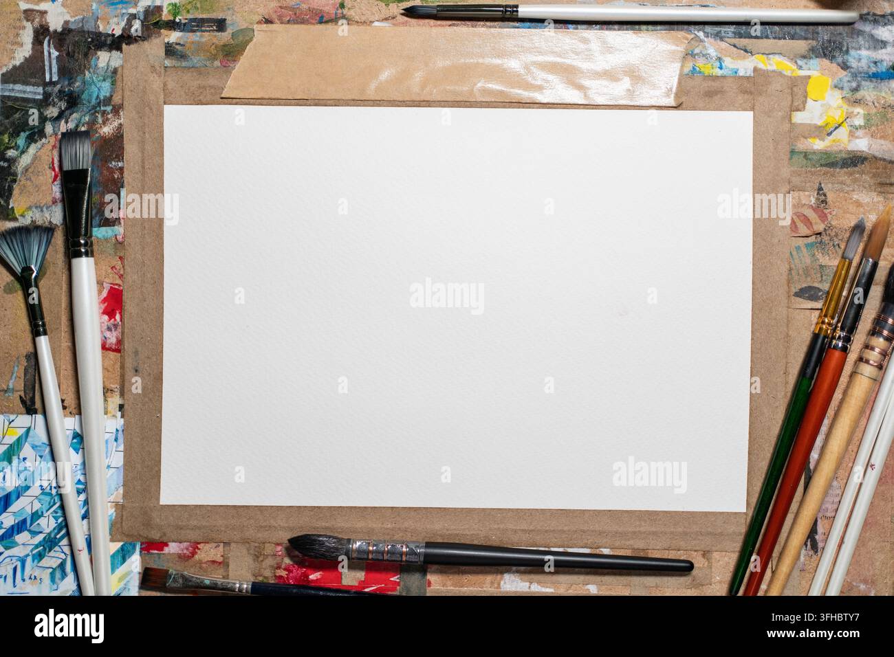 Carta acquerello attaccata su una tavola da disegno vintage in legno sporco con pennelli accanto Foto Stock