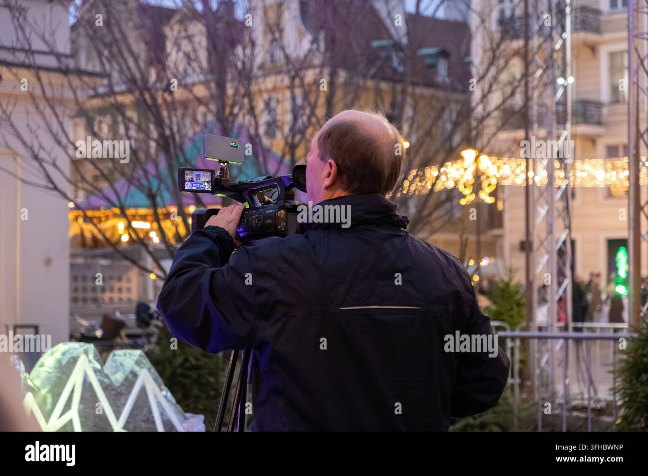 Pozna, Polonia – 13 dicembre 2025: Operatore che registra riprese di un evento all'aperto con una telecamera video professionale, catturando la celebrazione della festa pubblica Foto Stock