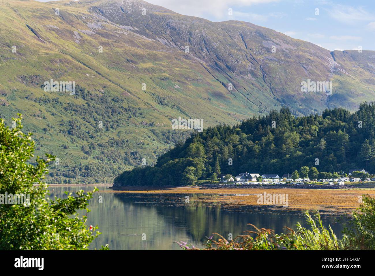 Il villaggio di Glencoe si affaccia sulle acque calme del Loch Leven in una tranquilla giornata estiva nelle Highlands scozzesi. Foto Stock