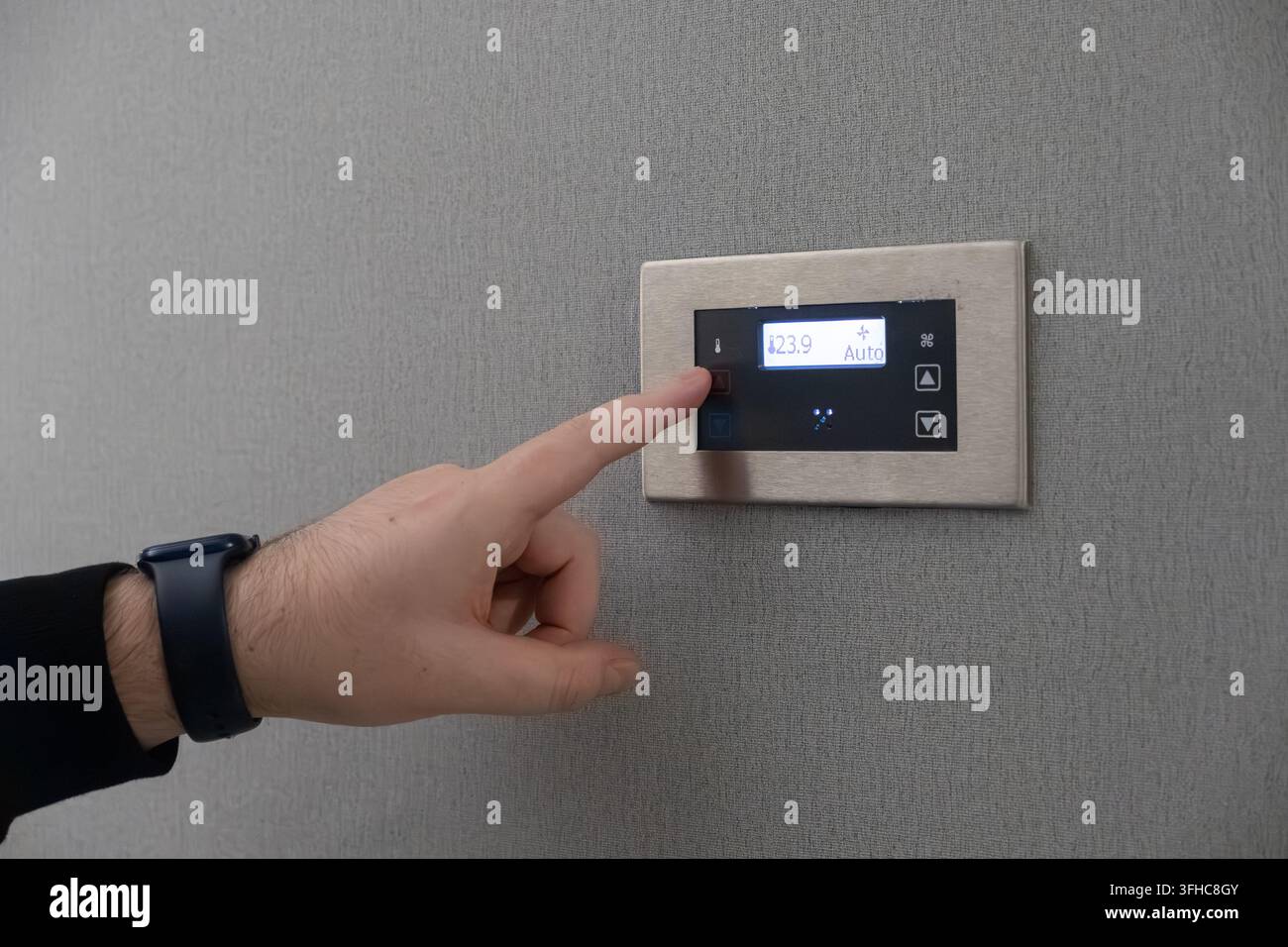 Persona che interagisce con un moderno regolatore di temperatura a schermo touch, dimostrando una gestione precisa dell'ambiente per il riscaldamento o il raffreddamento residenziale Foto Stock