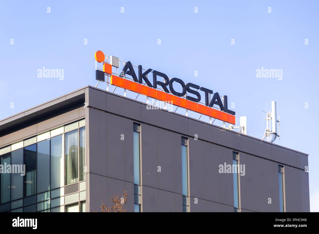 Poznań, Polonia – 15 dicembre 2025: Scritta del logo Akrostal montata sulla facciata grigia di un grattacielo per uffici, rappresentante l'identità aziendale e lo sviluppo urbano Foto Stock