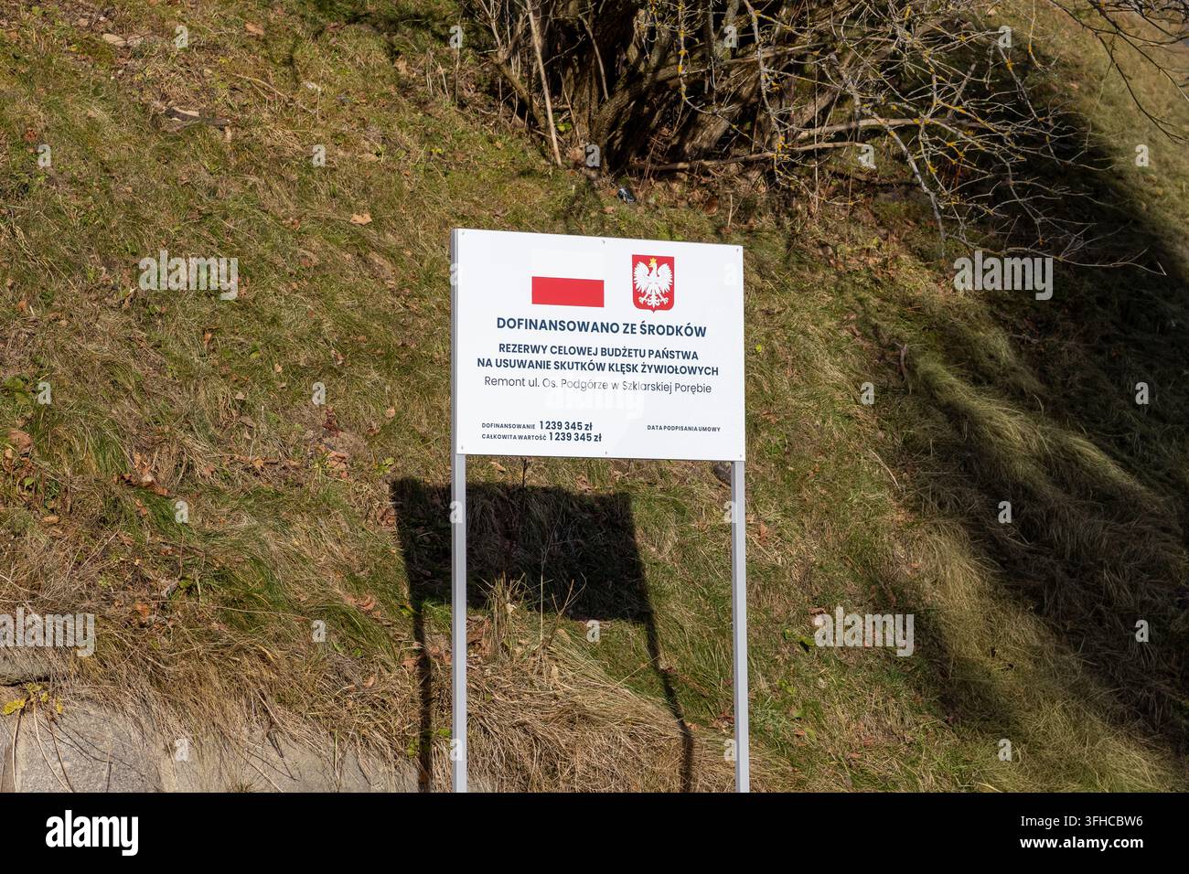 Szklarska Poręba, Polonia – 16 dicembre 2025: Cartello ufficiale con bandiera polacca mostra i fondi del bilancio statale per le iniziative di recupero dalle calamità naturali Foto Stock