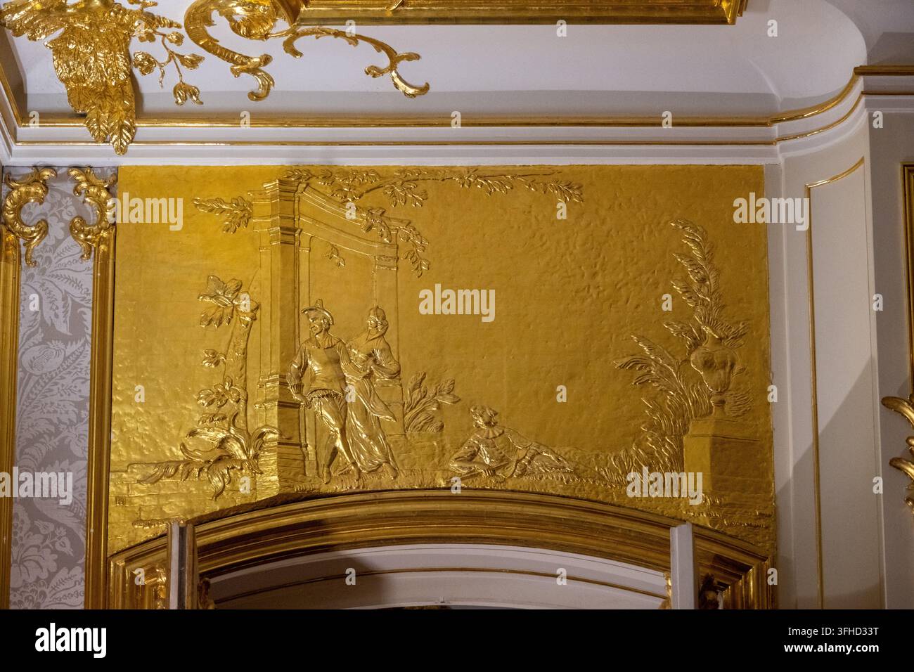 Berlino, Germania – 8 nov 25: Vista ravvicinata di un pannello a rilievo dorato con figure classiche all’interno del Castello di Charlottenburg a Berlino. Foto Stock